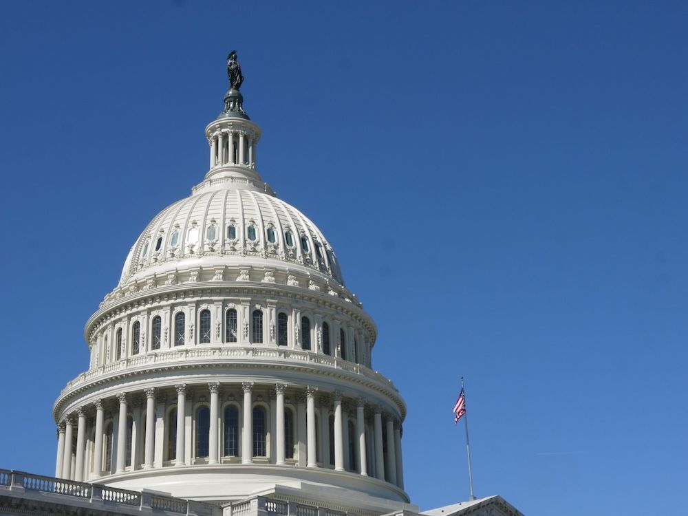 Imagen del edificio del Capitolio de los Estados Unidos con su icónica cúpula blanca y columnas neoclásicas, sobre un cielo azul despejado.