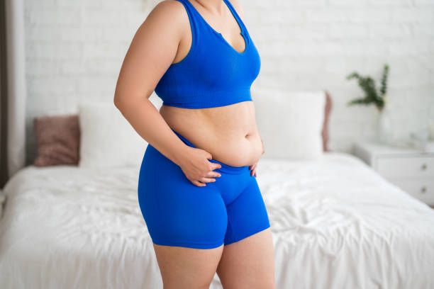 Mujer con grasa abdominal en ropa deportiva azul
